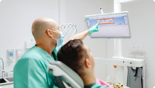 Oral surgeon reviewing a digital 3D model of the dental arches on a monitor during a pre-prosthetic surgery consultation for denture preparation